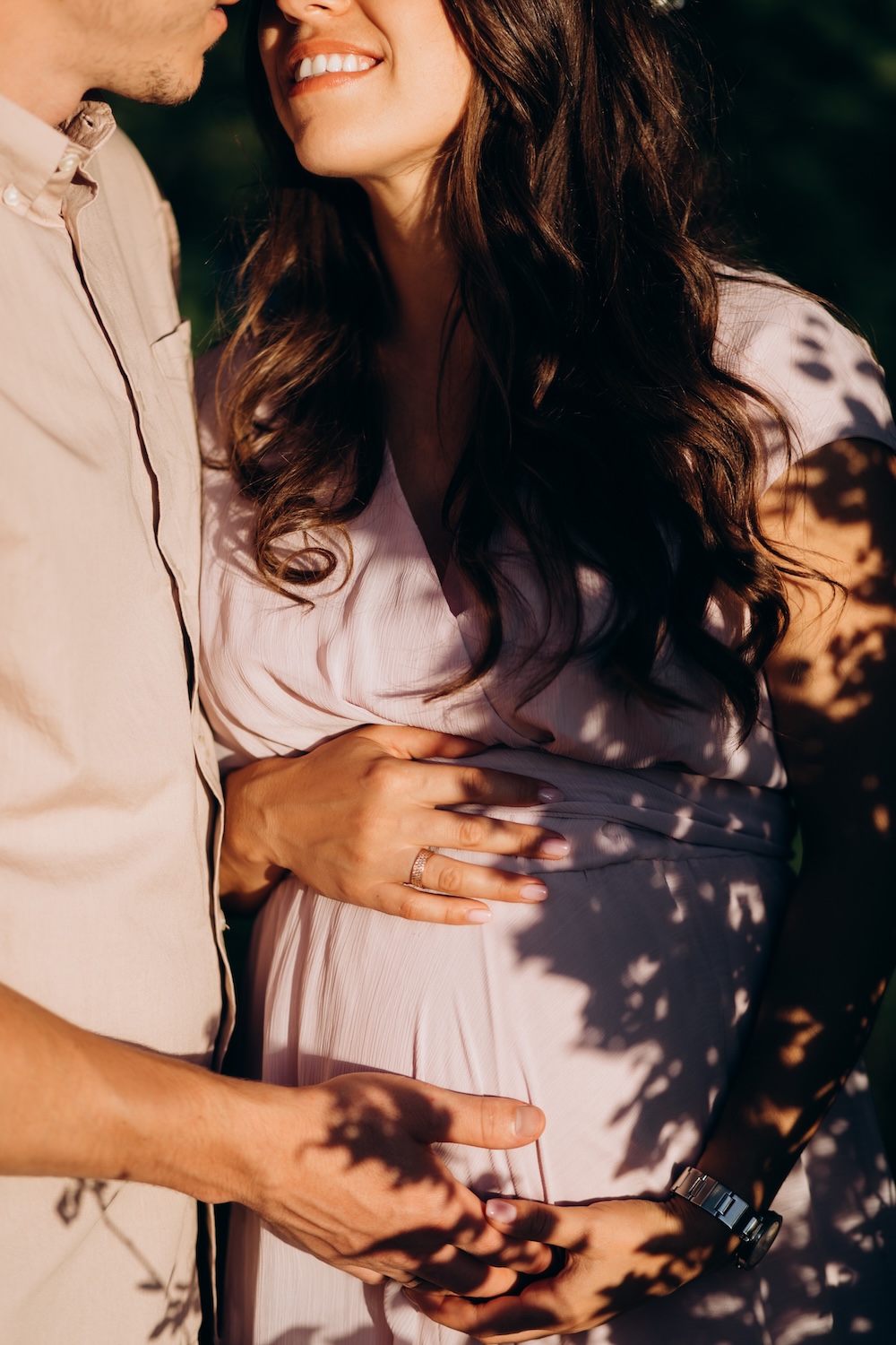 Man hugs beautiful pregnant woman tender standing before the lake in the rays of evening sun Kyncs